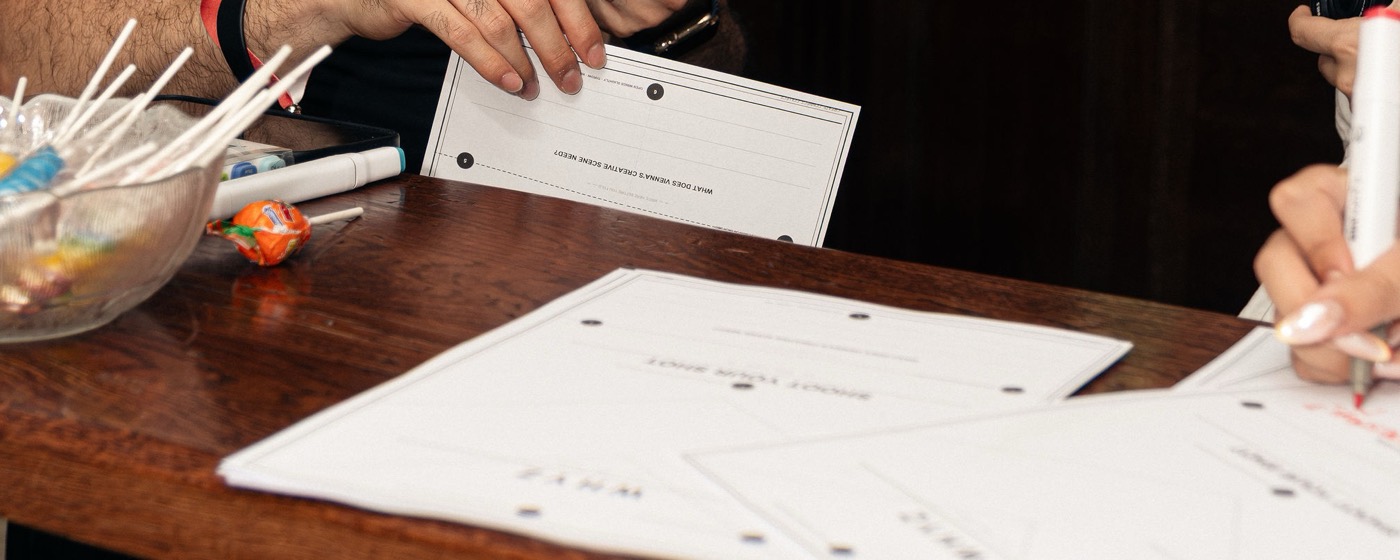 Printed collaboration cards spread across a wooden table at the door.