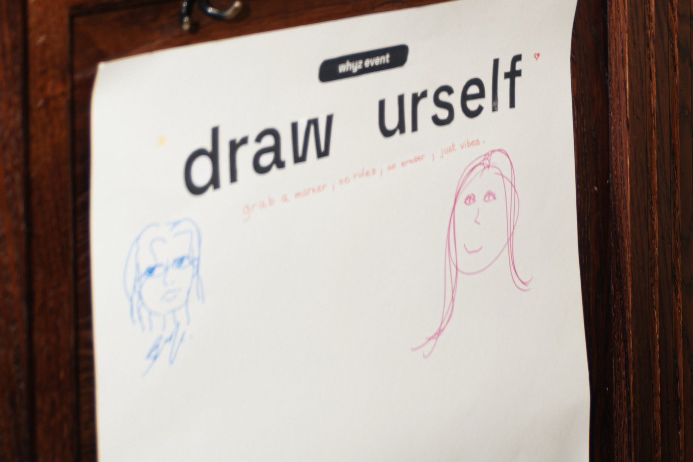 A hand-lettered paper sign reading draw urself, with two pencil portraits below it.