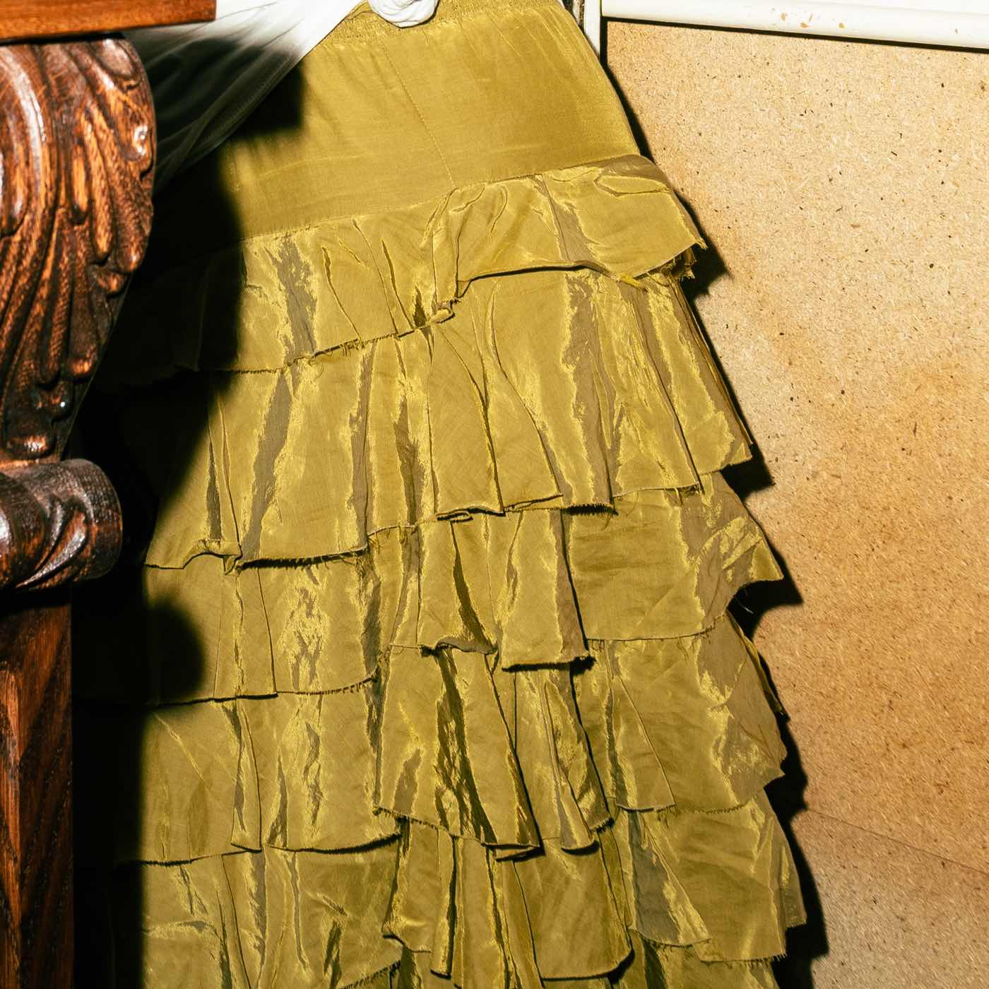 A gold ruffled satin skirt against dark wood.