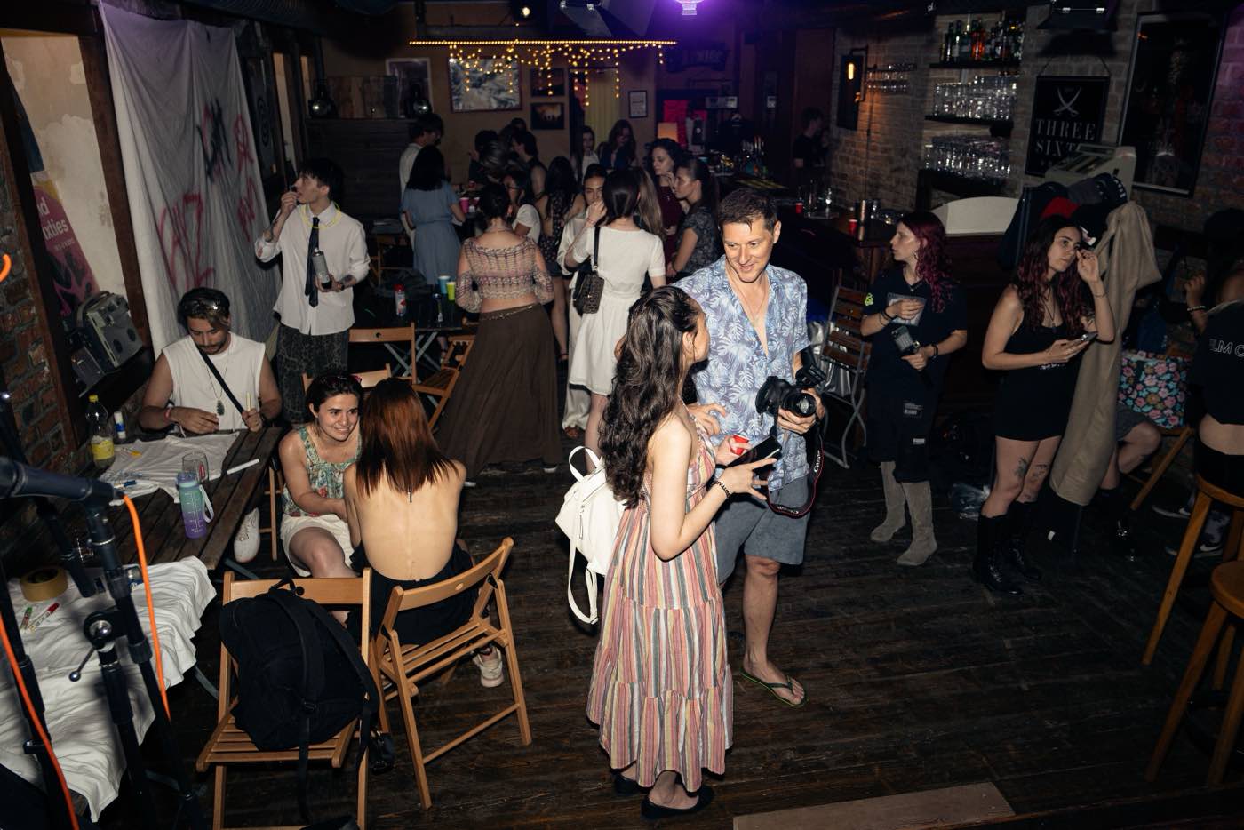 The full room at Vol. 01, guests standing and talking between the stage and the bar.