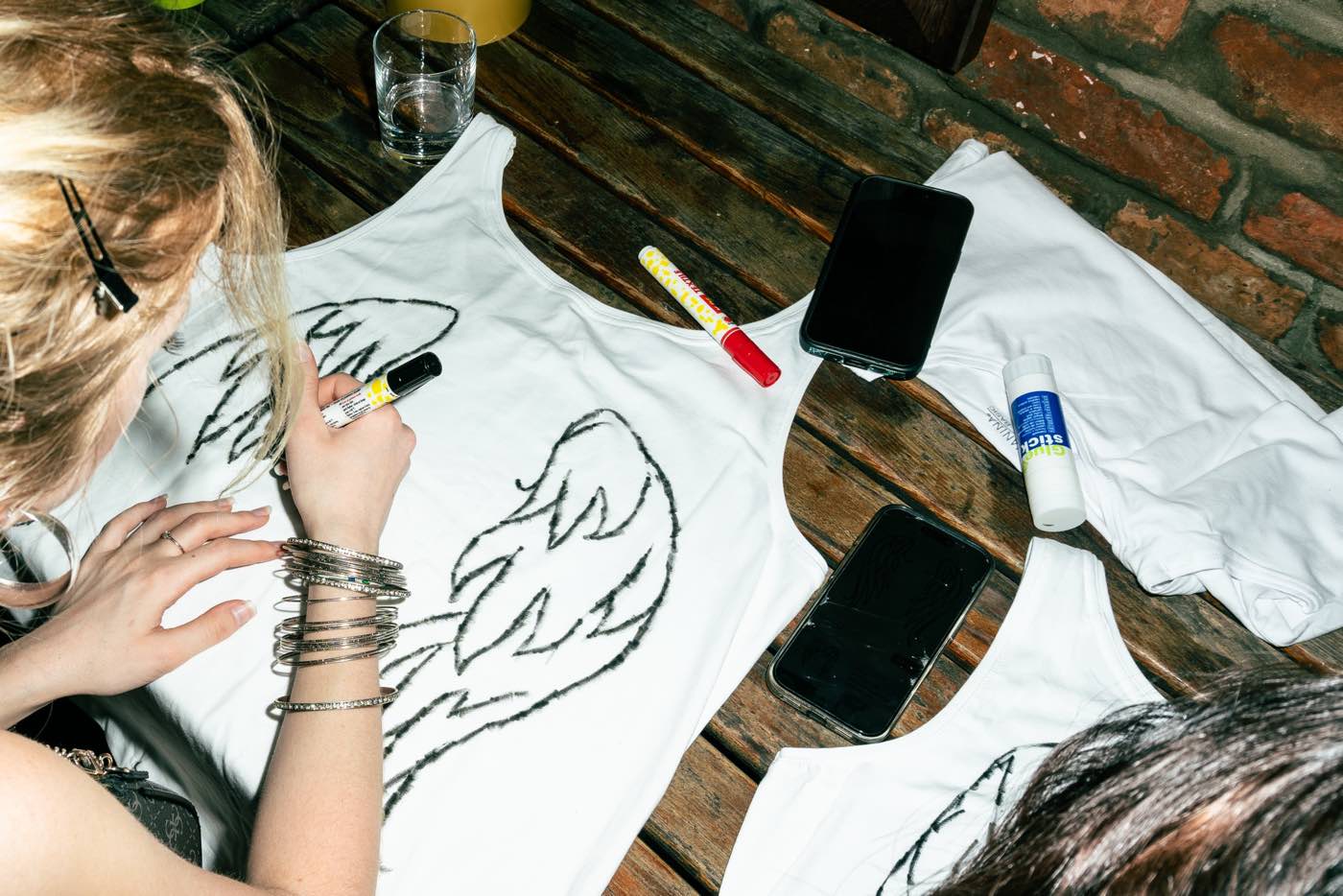 White vests drawn on with marker pens, laid across a wooden bench.